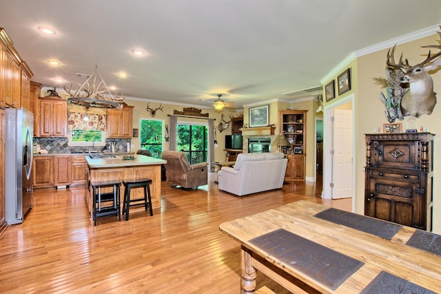 living room featuring light hardwood / wood-style flooring, ceiling fan with notable chandelier, and ornamental molding