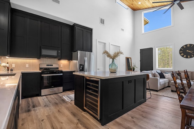 150 Tatanka Trl, Brookeland, TX 75931 - kitchen with dark cabinetry, stainless steel appliances, a high ceiling, light countertops, and light wood-style floors