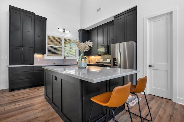 150 Tatanka Trl, Brookeland, TX 75931 - kitchen featuring stainless steel appliances, dark cabinets, a kitchen island, decorative backsplash, and a high ceiling