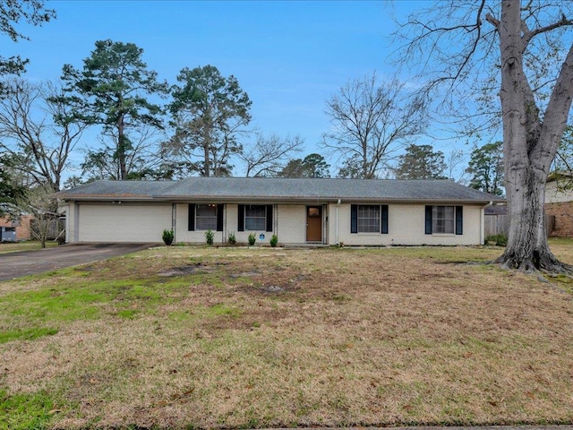 ranch-style house featuring an attached garage, brick siding, driveway, and a front yard