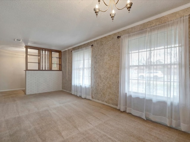 spare room with a textured ceiling, visible vents, and crown molding