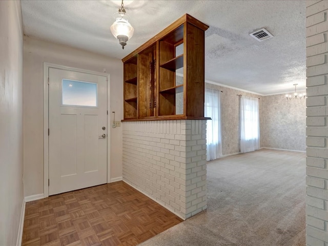 entryway featuring a textured ceiling, baseboards, visible vents, and a notable chandelier