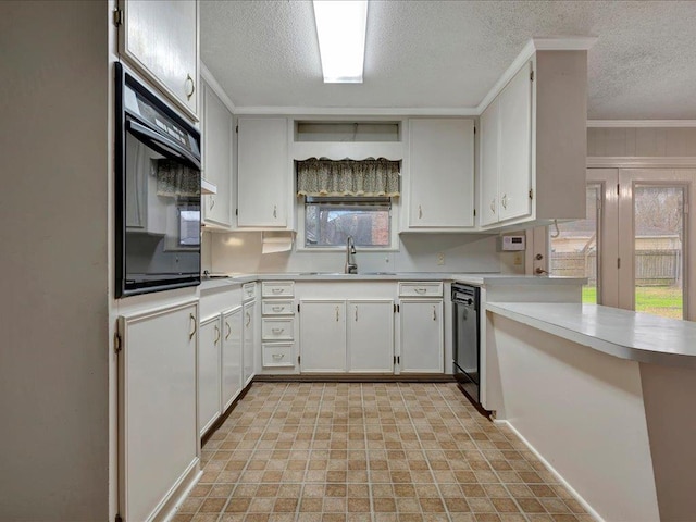 kitchen with a peninsula, light countertops, a textured ceiling, black appliances, and a sink