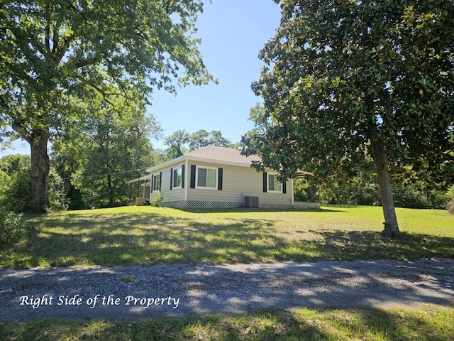 view of side of property with a yard and central AC