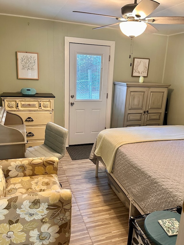 bedroom with light hardwood / wood-style flooring, ceiling fan, and wooden walls