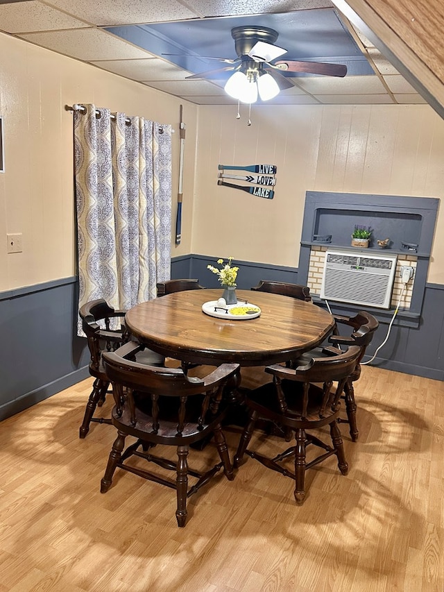 dining area with light hardwood / wood-style floors, a drop ceiling, cooling unit, and ceiling fan