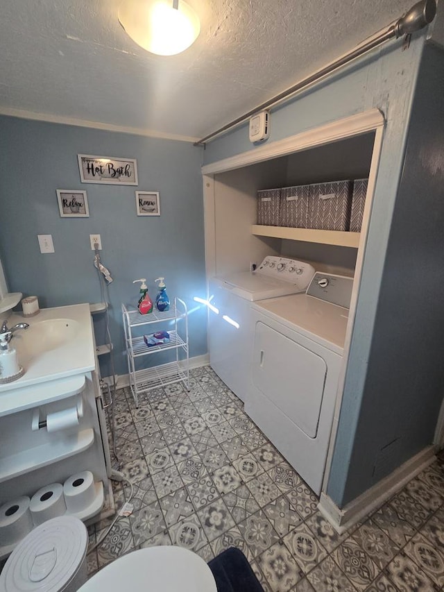 laundry area with a textured ceiling, washer and dryer, light tile patterned floors, and crown molding