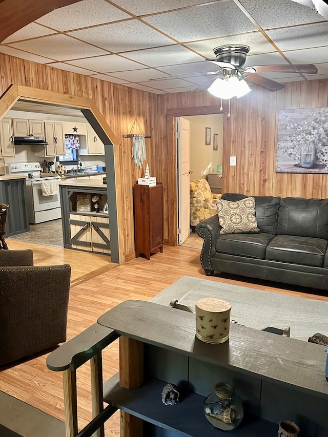 206 Perkins St, Zavalla, TX 75980 - living area with wood walls, a ceiling fan, light wood-style flooring, arched walkways, and a drop ceiling