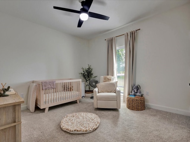 bedroom with ceiling fan, carpet floors, and a nursery area