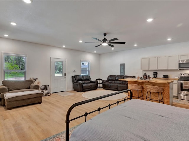 bedroom with electric panel, light hardwood / wood-style flooring, and ceiling fan