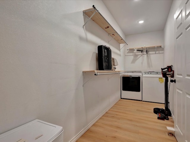 clothes washing area with washing machine and dryer and light hardwood / wood-style flooring