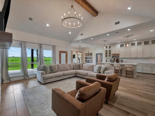 living room featuring beam ceiling, high vaulted ceiling, and a notable chandelier