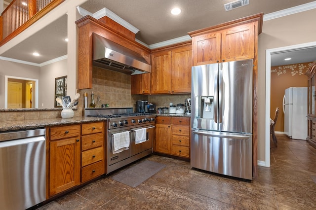 474 Mountain View Rd, Lufkin, TX 74904 - kitchen with appliances with stainless steel finishes, wall chimney exhaust hood, ornamental molding, decorative backsplash, and dark stone countertops