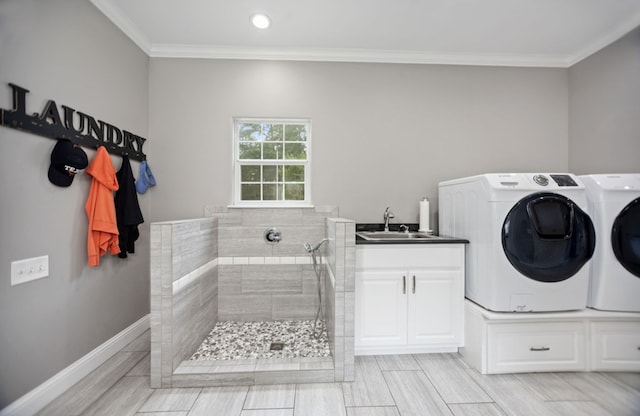laundry room featuring cabinet space, a sink, ornamental molding, and washer and clothes dryer