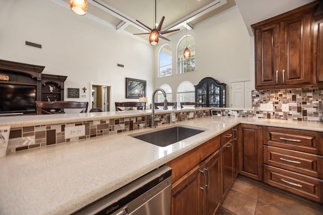 kitchen with ceiling fan, backsplash, a towering ceiling, dishwasher, and a sink
