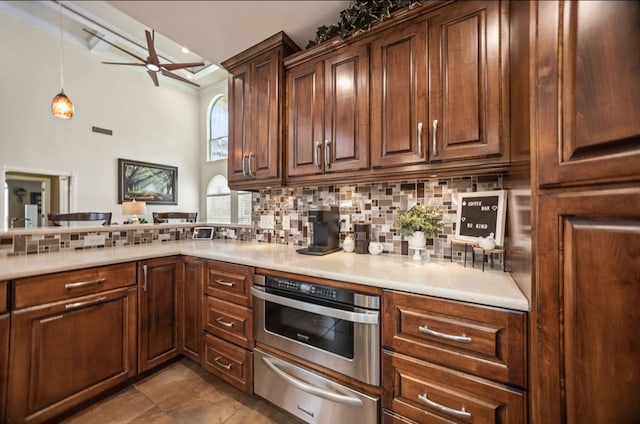 kitchen featuring decorative backsplash, a ceiling fan, a warming drawer, and light countertops