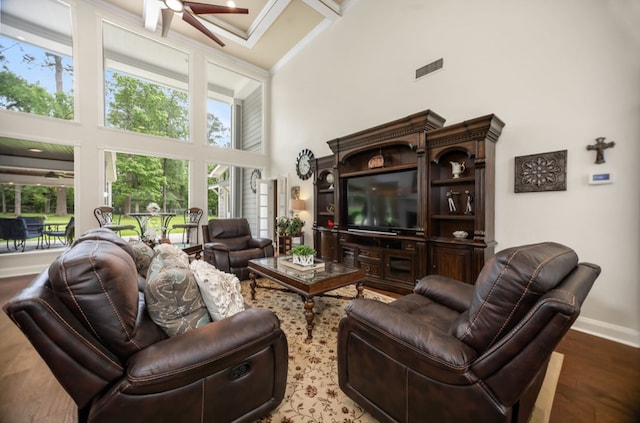 living area with visible vents, a towering ceiling, wood finished floors, baseboards, and a ceiling fan