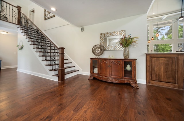 entryway with stairway, baseboards, and dark wood-type flooring