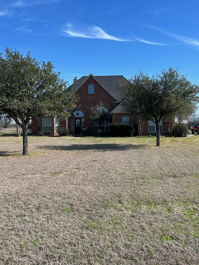 traditional home featuring brick siding and a front lawn