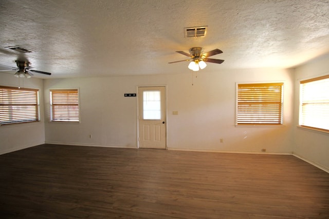 unfurnished room featuring a wealth of natural light, dark wood-type flooring, and ceiling fan