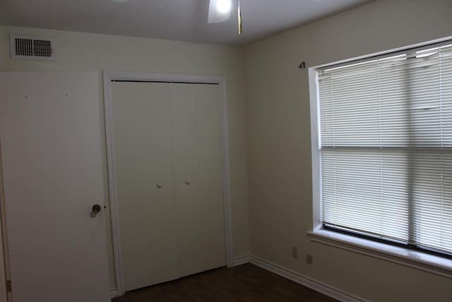 unfurnished bedroom with dark hardwood / wood-style flooring, ceiling fan, and a closet