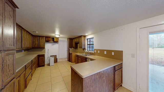 kitchen with kitchen peninsula, a textured ceiling, sink, light tile patterned floors, and built in desk