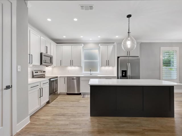 829 Village Gate Cir, Nacogdoches, TX 75961 - kitchen with appliances with stainless steel finishes, a center island, tasteful backsplash, ornamental molding, and light countertops
