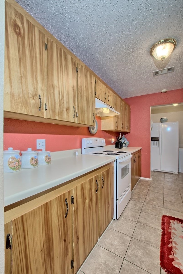 kitchen featuring light tile patterned floors, white appliances, and a textured ceiling