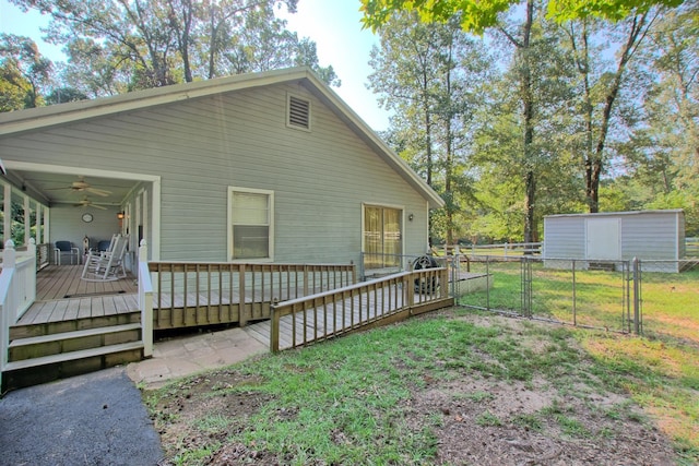 exterior space with a wooden deck, ceiling fan, a yard, and a storage shed