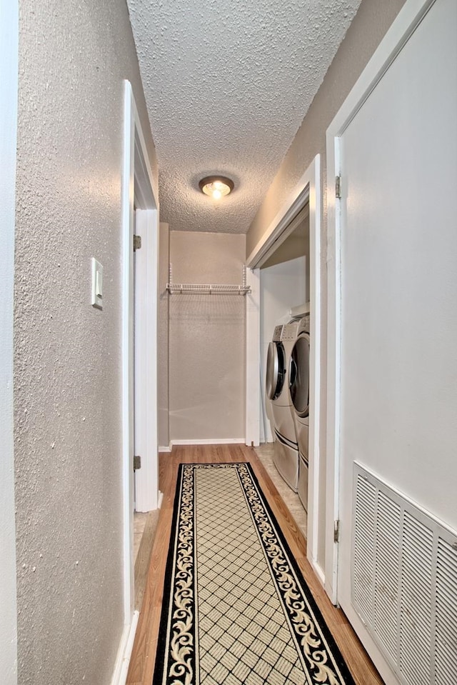 clothes washing area featuring light hardwood / wood-style floors, a textured ceiling, and independent washer and dryer