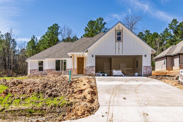 modern inspired farmhouse with a shingled roof, driveway, board and batten siding, and an attached garage