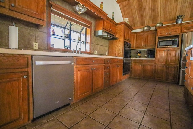 kitchen with brown cabinets, light countertops, under cabinet range hood, appliances with stainless steel finishes, and tasteful backsplash