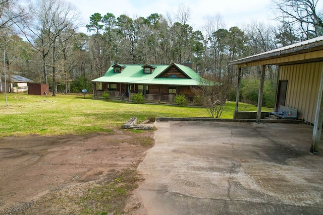 view of front of home featuring an outbuilding, driveway, a front lawn, a porch, and metal roof