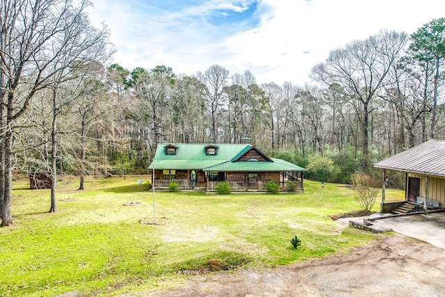 view of front of home featuring a front lawn, covered porch, dirt driveway, and metal roof