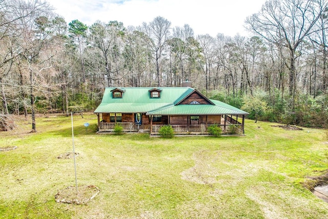 chalet / cabin with a front lawn, driveway, covered porch, metal roof, and a chimney