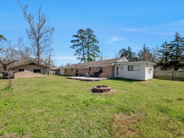 rear view of property with a fire pit, french doors, a lawn, and fence