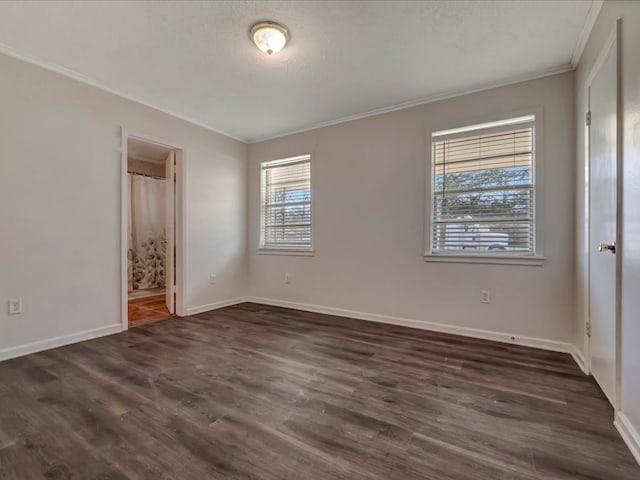 unfurnished bedroom featuring ensuite bath, baseboards, ornamental molding, and dark wood finished floors