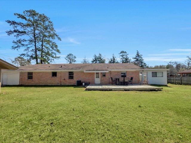 rear view of property with brick siding, a yard, a wooden deck, and fence