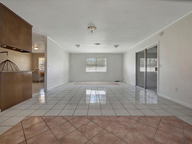 unfurnished room with baseboards, ornamental molding, and light tile patterned flooring