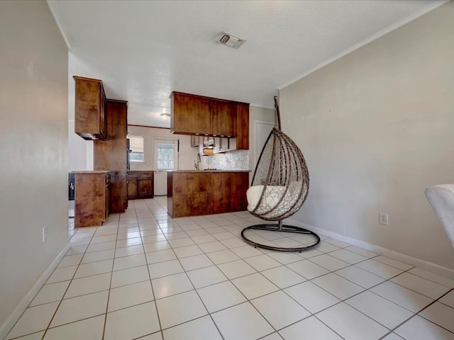 kitchen featuring brown cabinets, light countertops, visible vents, light tile patterned flooring, and a peninsula