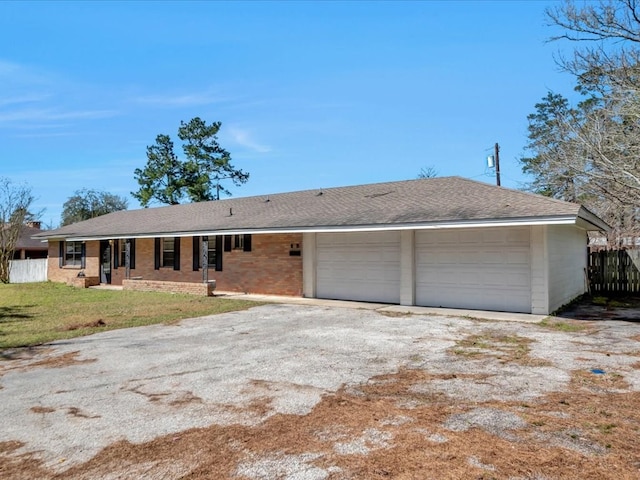 ranch-style house with a garage, a shingled roof, fence, driveway, and a front yard