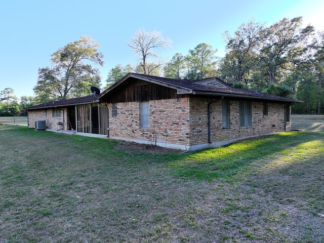 view of home's exterior with cooling unit, a yard, and brick siding