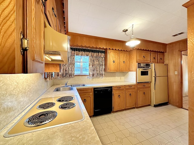 kitchen featuring white appliances, brown cabinetry, light countertops, and a sink