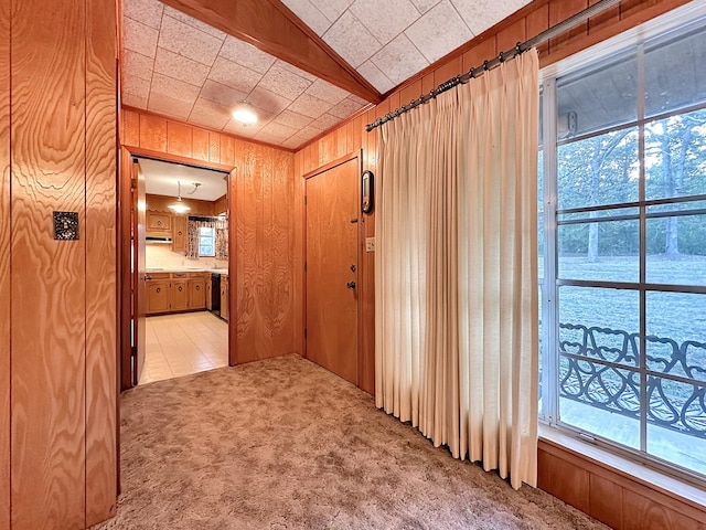 hall featuring light carpet and wood walls