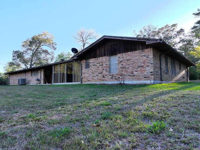 view of property exterior with central AC unit, brick siding, and a lawn