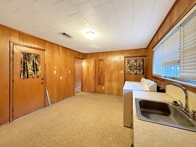 laundry area with a sink, light colored carpet, washing machine and dryer, and wooden walls
