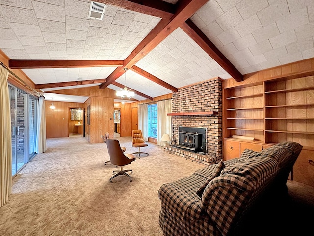 living room with visible vents, lofted ceiling with beams, wood walls, a fireplace, and carpet flooring