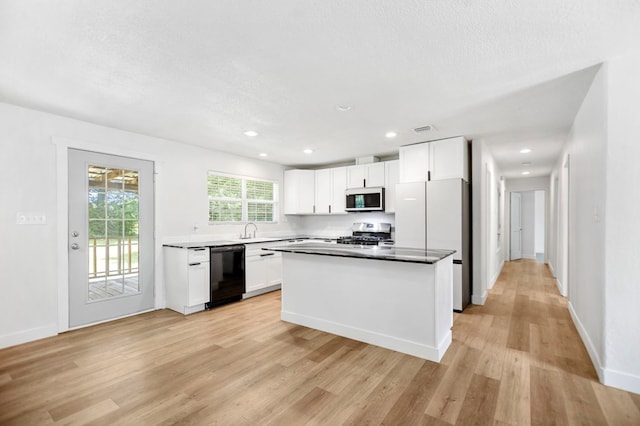175 Weeks St, Lufkin, TX 75904 - kitchen featuring white appliances, light wood-type flooring, white cabinetry, a kitchen island, and recessed lighting