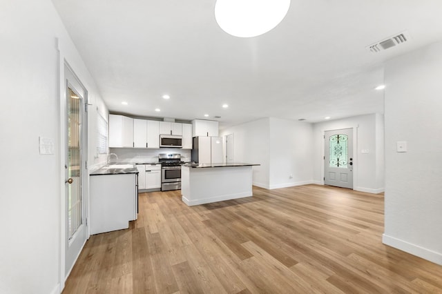 175 Weeks St, Lufkin, TX 75904 - kitchen with stainless steel range with gas stovetop, freestanding refrigerator, dark countertops, light wood-type flooring, and recessed lighting
