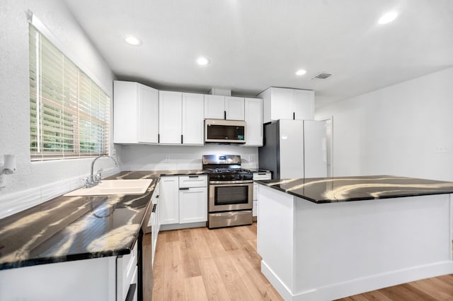175 Weeks St, Lufkin, TX 75904 - kitchen featuring white appliances, dark countertops, white cabinets, light wood-type flooring, and recessed lighting